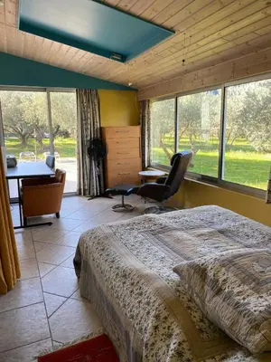 a bedroom with a bed and a desk and windows at Danie, maison des oliviers et vue Luberon in Maubec
