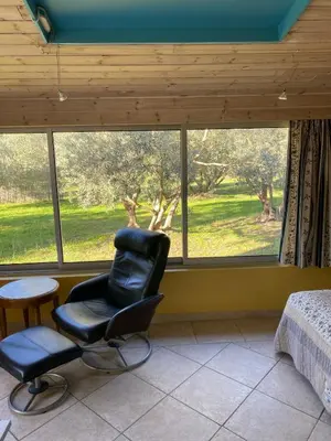 a bedroom with a chair in front of a window at Danie, maison des oliviers et vue Luberon in Maubec