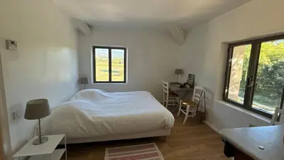 a bedroom with a bed and a desk and windows at Le Mas des Grillons, mas rénové entièrement climatisé avec piscine et vue Ventoux in Crillon-le-Brave