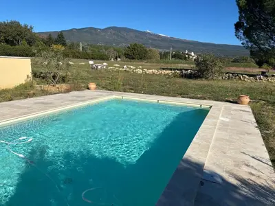 a blue swimming pool with a view of a field at Le Mas des Grillons, mas rénové entièrement climatisé avec piscine et vue Ventoux in Crillon-le-Brave
