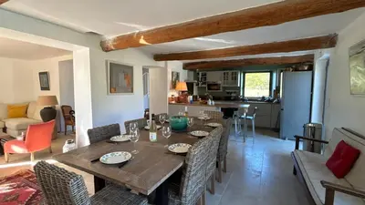 a dining room and kitchen with a wooden table and chairs at Le Mas des Grillons, mas rénové entièrement climatisé avec piscine et vue Ventoux in Crillon-le-Brave