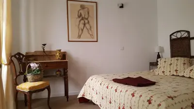 a bedroom with a bed and a table and a chair at Les Roues de L'Isle - CHARMING APARTMENT in LʼIsle-sur-la-Sorgue