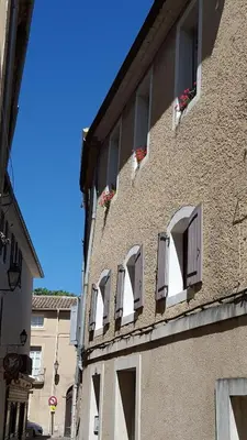 a building with windows and flowers on the side of it at Les Roues de L'Isle - CHARMING APARTMENT in LʼIsle-sur-la-Sorgue