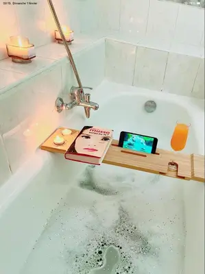 a bathroom with a bath tub with a tablet and a book at appartement de charme au coeur d'aix en provence in Aix-en-Provence