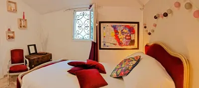 a bedroom with a bed with red pillows and a window at Charmant studio aux portes des Alpilles in Eyguières