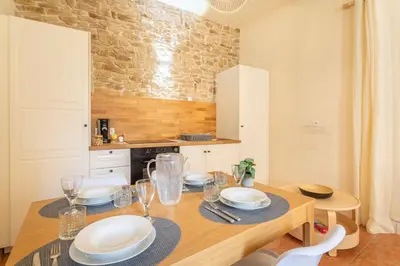 a kitchen with a wooden table with plates and glasses at Le Petit Saint Esprit, centre, calme, lumineux in Aix-en-Provence