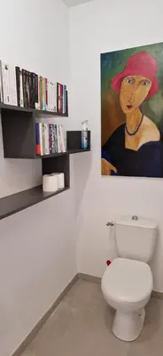 a bathroom with a toilet and a painting on the wall at superbe escapade au cœur de la ville clim parking et piscine in Aix-en-Provence