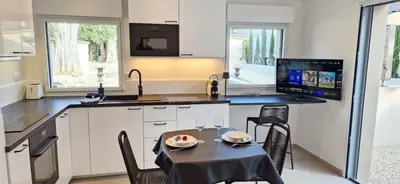 a kitchen with a table and chairs and a kitchen with a television at superbe escapade au cœur de la ville clim parking et piscine in Aix-en-Provence