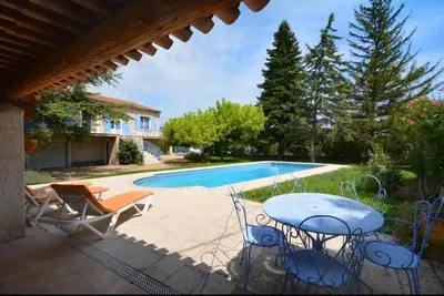 a patio with a table and chairs next to a swimming pool at Les Volets Bleus Provençal house with pool in LʼIsle-sur-la-Sorgue