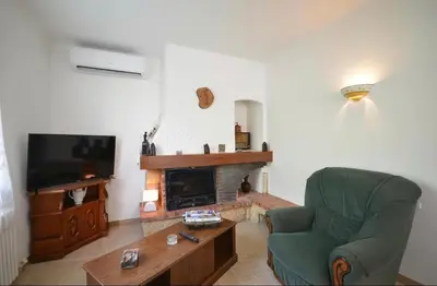 a living room with a green chair and a television at Les Volets Bleus Provençal house with pool in LʼIsle-sur-la-Sorgue