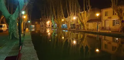 a city street at night with a reflection in the water at La maison de la lumière in Cucuron