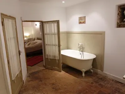a bathroom with a bath tub and a bedroom at La maison de la lumière in Cucuron