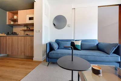 a living room with a blue couch and a table at Downtown suite, parking, loggia, elevator, quiet in Aix-en-Provence