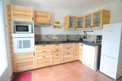 a kitchen with wooden cabinets and white appliances at Le Petit Pont - Au bord de la rivière in LʼIsle-sur-la-Sorgue