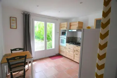 a kitchen with a table and a refrigerator at Le Petit Pont - Au bord de la rivière in LʼIsle-sur-la-Sorgue