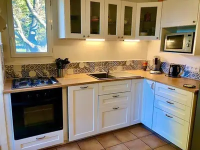 a kitchen with white cabinets and a stove top oven at Le Castor et La Loutre - Gites en bord de Sorgue in LʼIsle-sur-la-Sorgue