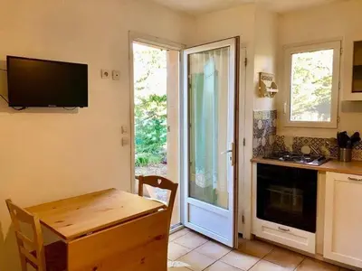a kitchen with a table and a television on the wall at Le Castor et La Loutre - Gites en bord de Sorgue in LʼIsle-sur-la-Sorgue