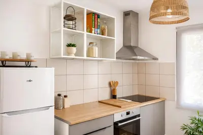 a kitchen with white cabinets and a white refrigerator at Appartement 4 personnes 5 minutes a pieds du centre ville parking gratuit jardin 85m2 in LʼIsle-sur-la-Sorgue