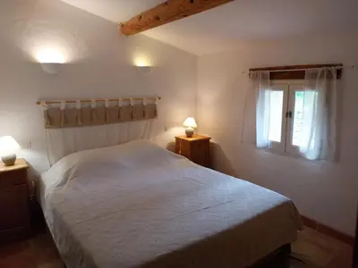 a bedroom with a white bed and a window at le Mas caché in Ménerbes