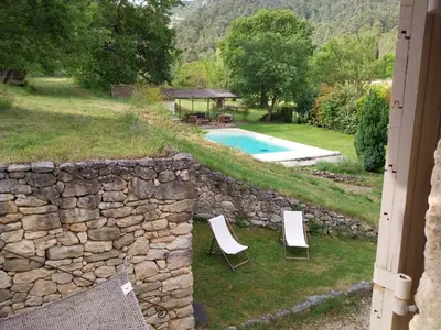 a stone wall with two chairs and a swimming pool at le Mas caché in Ménerbes
