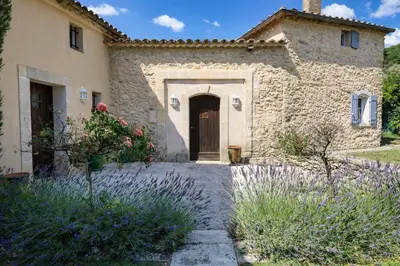 a stone house with a door in a yard at La Grange Blanche in Sault-de-Vaucluse