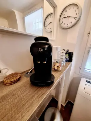 a coffee maker on a counter in a kitchen with clocks at Le Cocon d'Emy in Aix-en-Provence