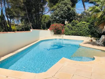 a swimming pool with blue water in a backyard at Une maison provençale dans la pinède - A Provençal house in a pine forest in Lambesc