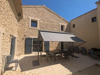 a patio with a table and chairs in front of a building at La Ferme Au bord de l etang de la Bonde in Sannes
