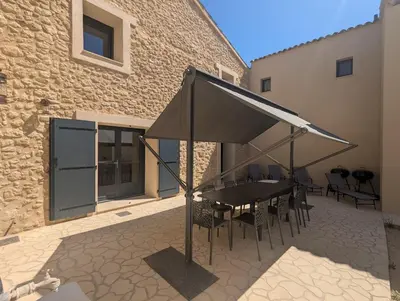 a patio with a table and chairs under a canopy at La Ferme Au bord de l etang de la Bonde in Sannes