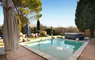 a swimming pool with an umbrella and a television at Maison Avec Piscine Privée in Entraigues-sur-la-Sorgue
