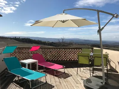 a group of chairs and an umbrella on a deck at Maison Les Bruns, sur la route du Mont Ventoux in Bédoin