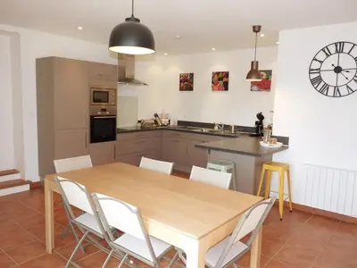 a kitchen and dining room with a wooden table and chairs at Maison Les Bruns, sur la route du Mont Ventoux in Bédoin