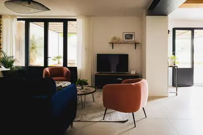a living room with a couch and chairs and a tv at Le mas des cerisiers - piscine chauffée in Caumont-sur-Durance
