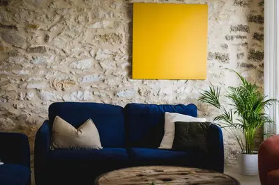 a blue couch in a living room with a yellow picture at Le mas des cerisiers - piscine chauffée in Caumont-sur-Durance
