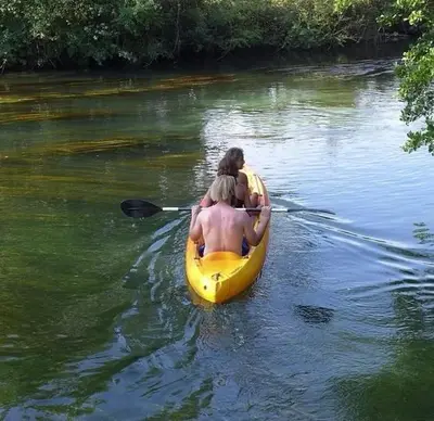 two people in a yellow kayak on a river at Les terrasses di Matt et eaux in LʼIsle-sur-la-Sorgue