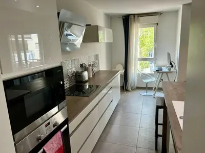 a kitchen with a stove top oven next to a table at Modern City Center apartment with parking! in Aix-en-Provence