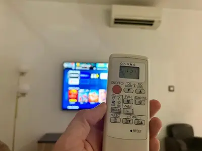 a hand holding a remote control in front of a tv at Modern City Center apartment with parking! in Aix-en-Provence