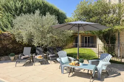 a patio with chairs and a table and an umbrella at Mas Caumontois Provençal charm & private pool in Caumont-sur-Durance