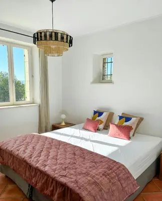 a bedroom with a large white bed with pink pillows at Family Stone House In Gordes in Gordes