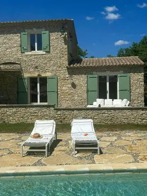 two lounge chairs sitting next to a swimming pool at Family Stone House In Gordes in Gordes