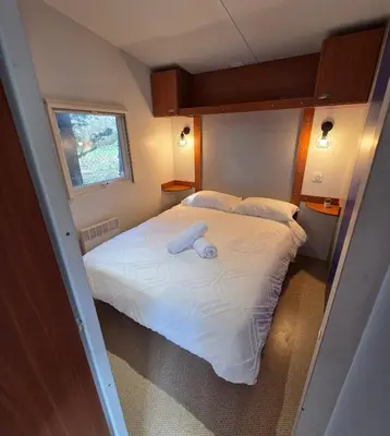 a small bedroom with a bed with white sheets at Mobile Home Pro - 4 personnes et parking in Pélissanne
