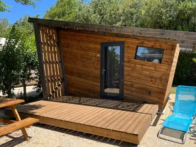 a wooden cabin with a table and a blue chair at Mobil-home confortable, 2 chambres, 4 personnes - API-1-52-1390 in Cavaillon