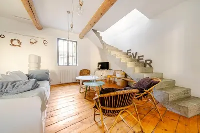 a living room with a staircase and a table and chairs at Charmante maison de village avec cour intérieure in Bédoin