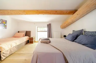 two beds in a room with white walls and wooden beams at Charmante maison de village avec cour intérieure in Bédoin