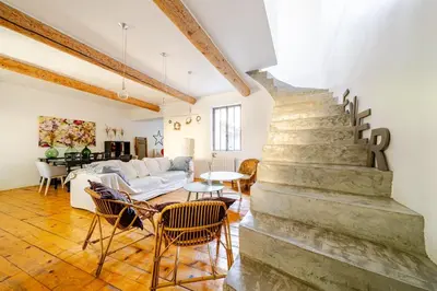 a living room with a staircase and a couch and chairs at Charmante maison de village avec cour intérieure in Bédoin