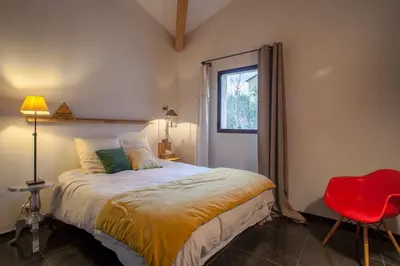 a bedroom with a bed and a red chair at La Maison des Restanques in Cabrières-dʼAvignon