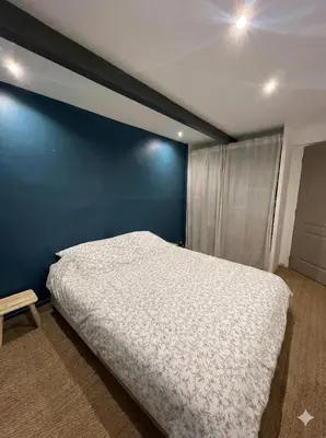 a bedroom with a bed and a blue wall at Maison de ville climatisée avec toit-terrasse privatif in Monteux