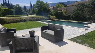 a swimming pool with two wicker chairs in a yard at Villa la grande Bastide in Oppède