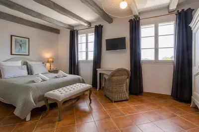 a bedroom with a bed and a chair and windows at Bastide Vallonia Luxury & Serenity in the Heart of the Luberon in Murs