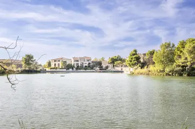 a view of a lake with houses in the background at Village Pont Royal en Provence - maeva Home - Appartement climatisé 4 pièces 6 personnes - Sélection - super Home MAE-7473 in Mallemort